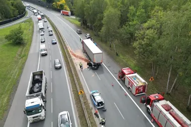 Służby ratunkowe interweniują przy wypadku z udziałem ciężarówki i samochodu osobowego na wielopasmowej drodze szybkiego ruchu otoczonej lasem.